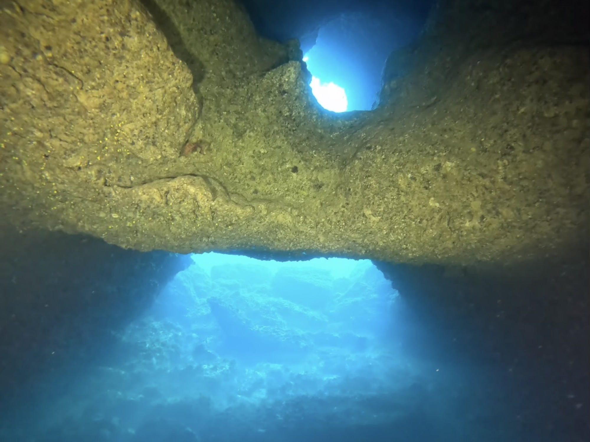 Looking up through a cave opening to surface light while diving in Mallorca