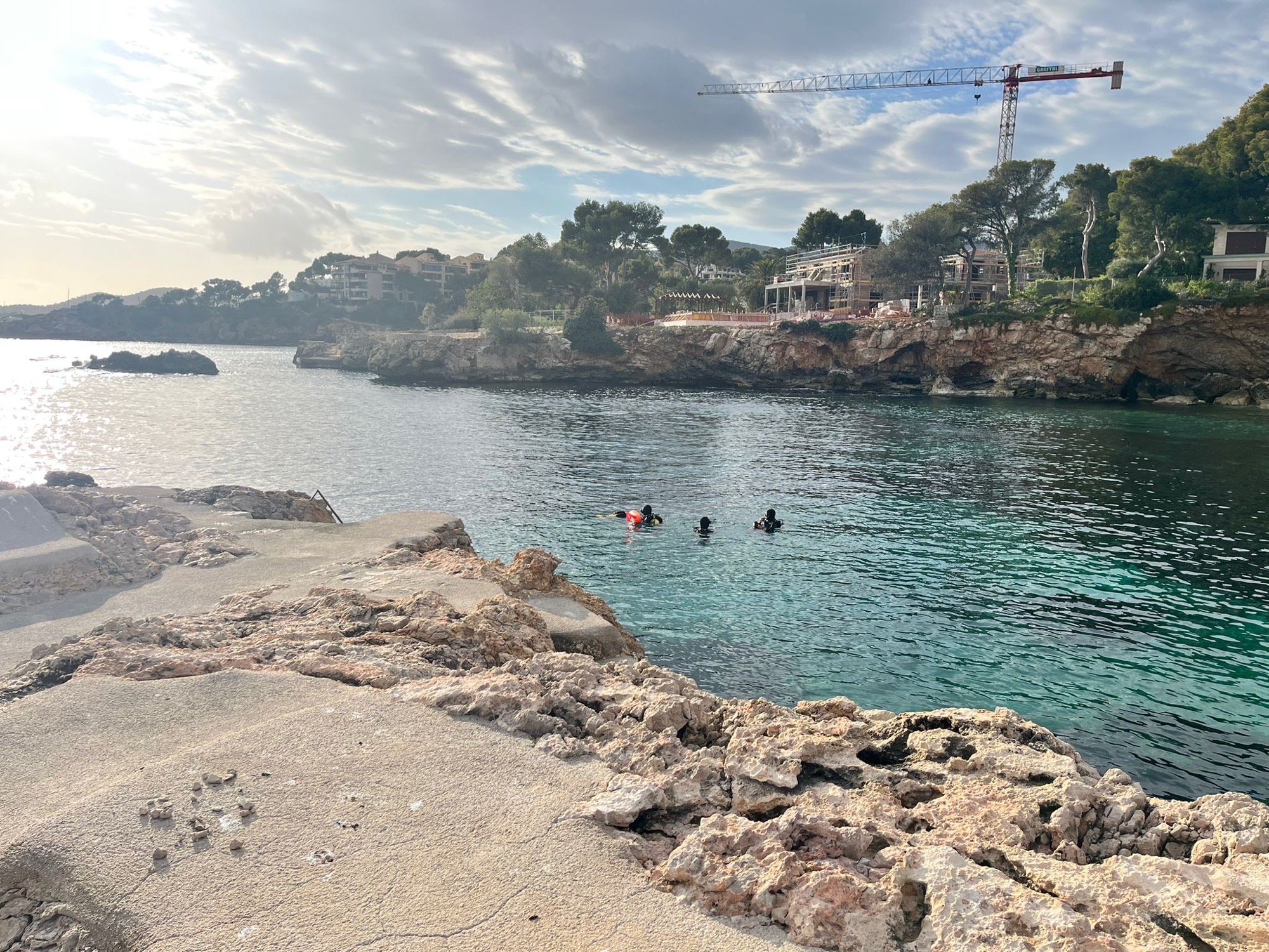 Divers on the surface in a rocky Mallorca cove before descending