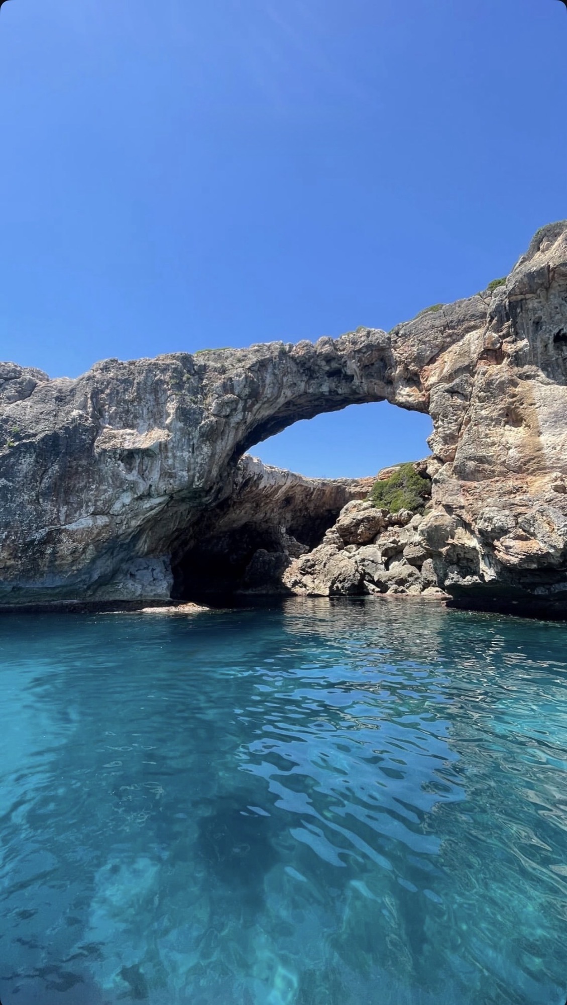 Natural rock arch over turquoise water on the Mallorca coastline